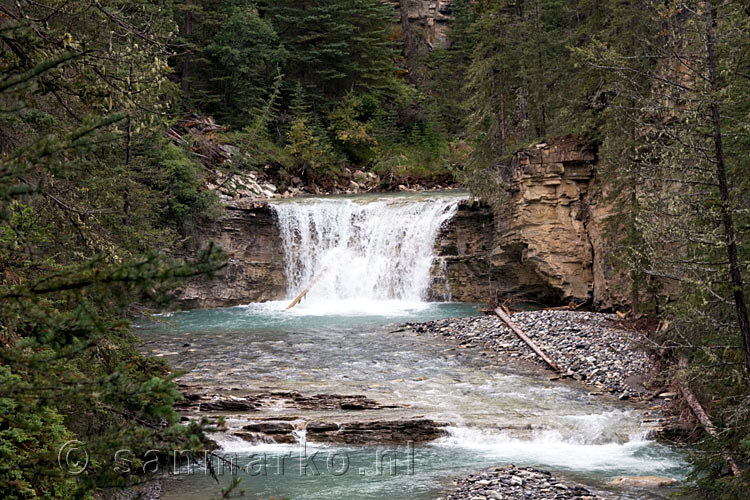 Een brede waterval langs het wandelpad door Johnston Canyon