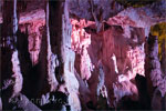Mooie vormen van stalactieten en stalagmieten door paars licht beschenen