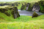 Het groene gras en de donkere stenen in de kloof Fjaðrárgljúfur