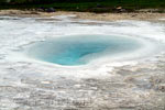 Een oude geiser met helder blauw water en lagen van kalk bij Hveravellir