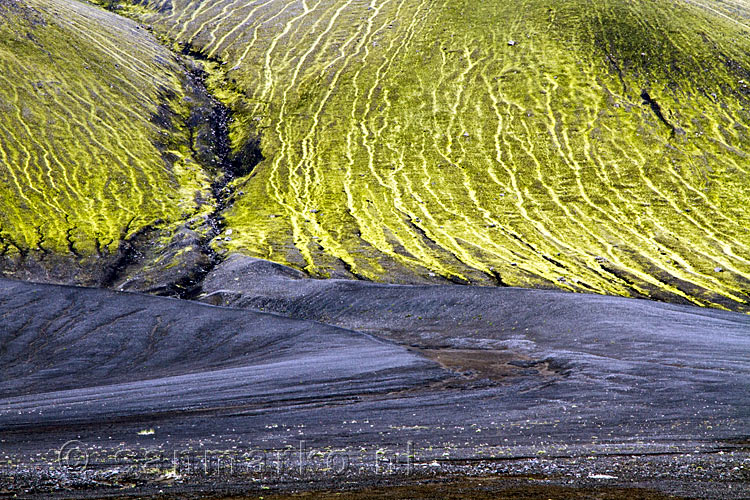 De git zwarte lava met gif groen mos langs de F 208 op IJsland