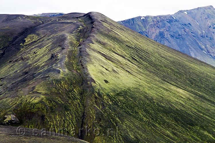 Een mooie watergeul tussen groen en zwart in Landmannalaugar in IJsland