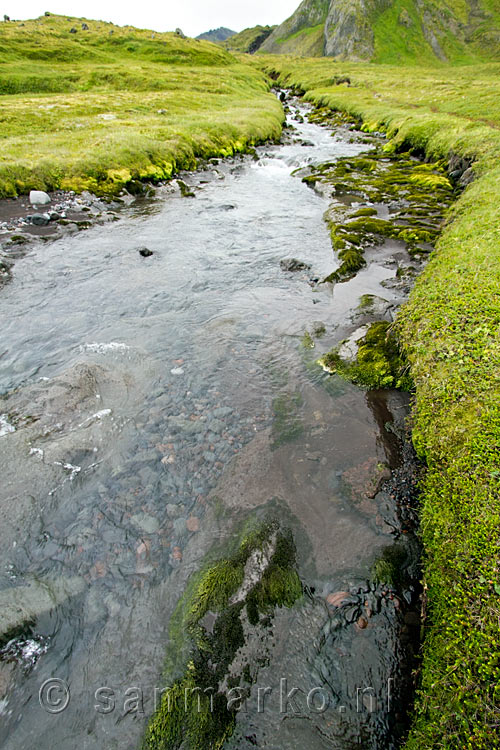 Vlakbij de auto wordt het groene landschap onderbroken door de beek bij Rauðhóll