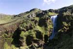 De half verscholen waterval gezien vanaf het wandelpad bij Skógar in IJsland