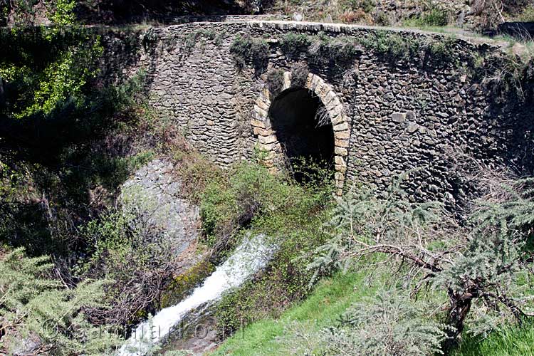 Een kleine waterval onder een onverharde weg bij Area recreativa Puente Palo